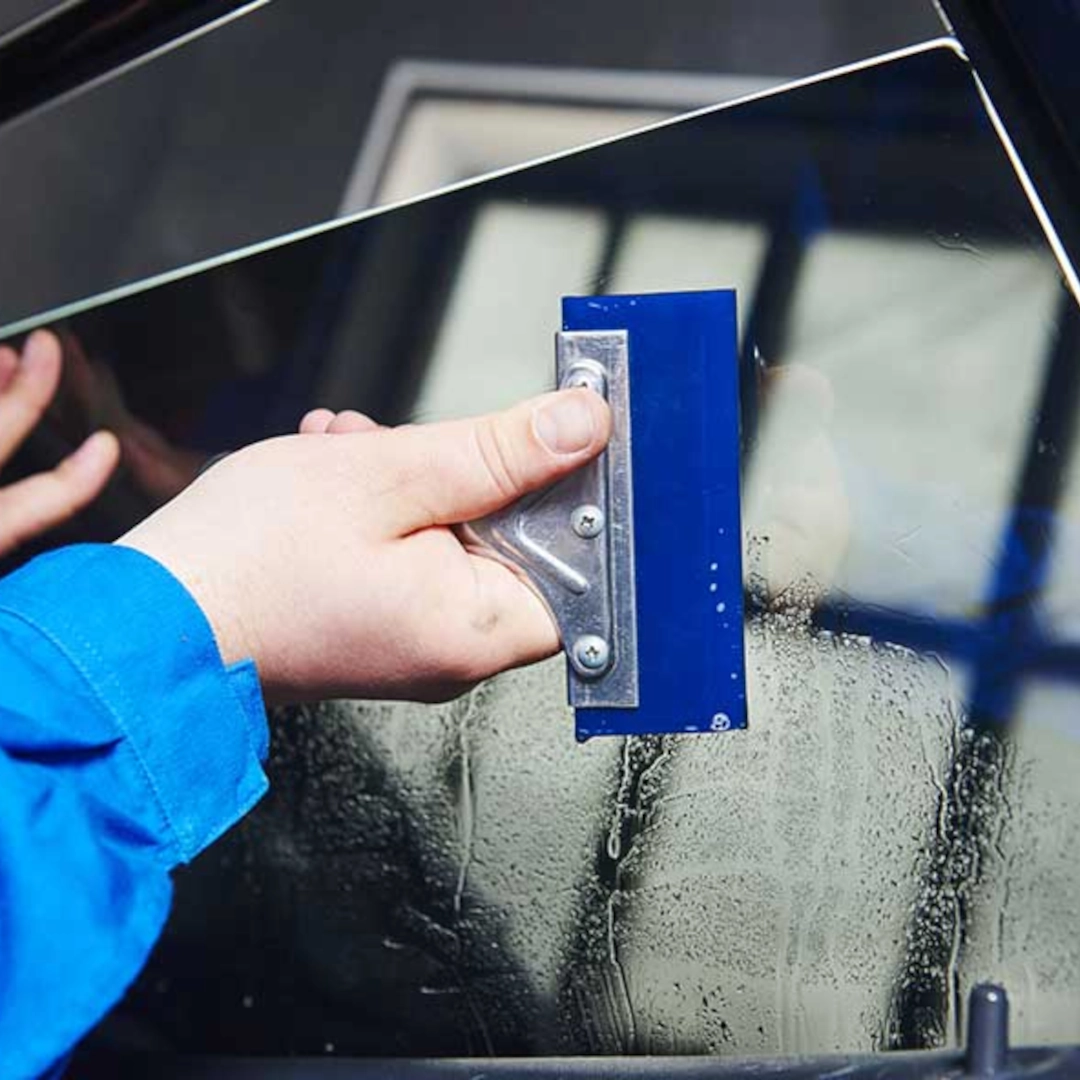 A window tinting technician is applying window tint to a vehicle