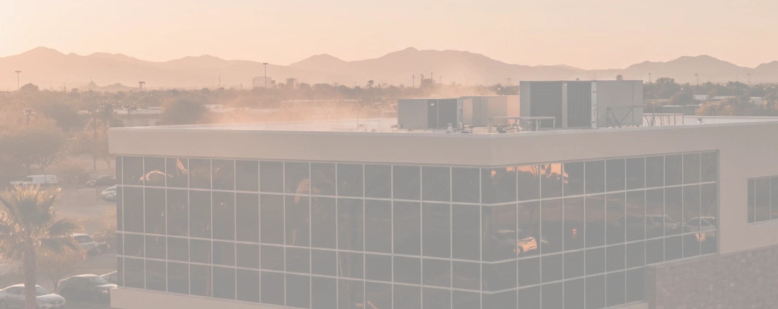 Modern 2-story Arizona commercial office building with west-facing glass and rooftop HVAC units, demonstrating solar heat gain
